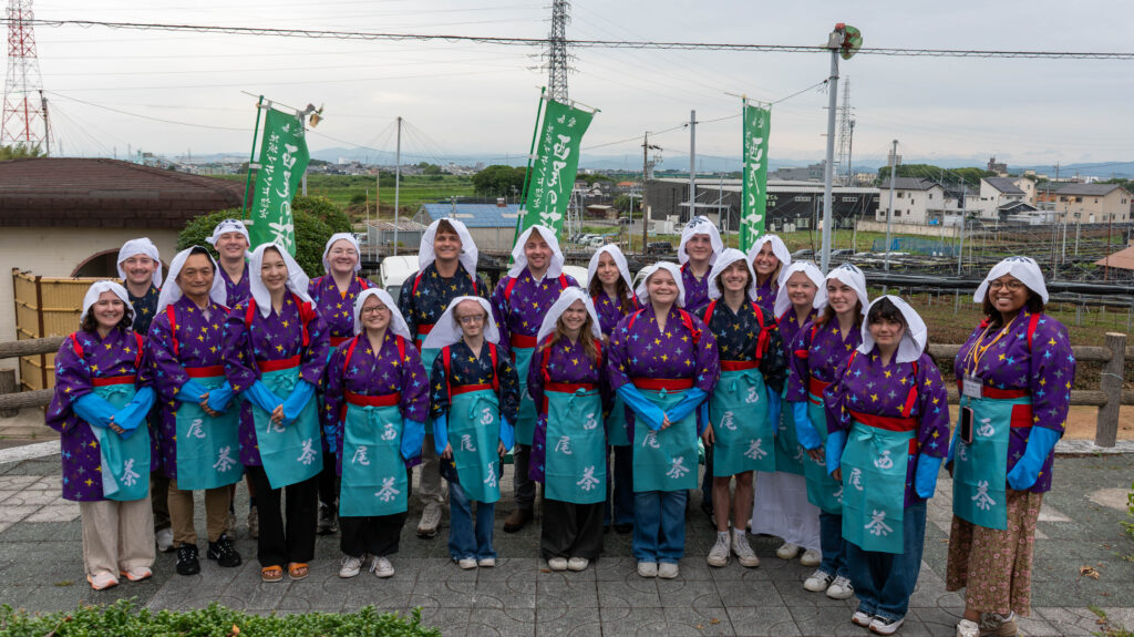 A group of students posed for a photo, all dressed in traditional attire for picking tea leaves.