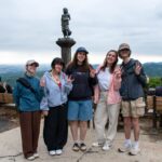 Five students are smiling for a photo with Mt.Takao in the background.
