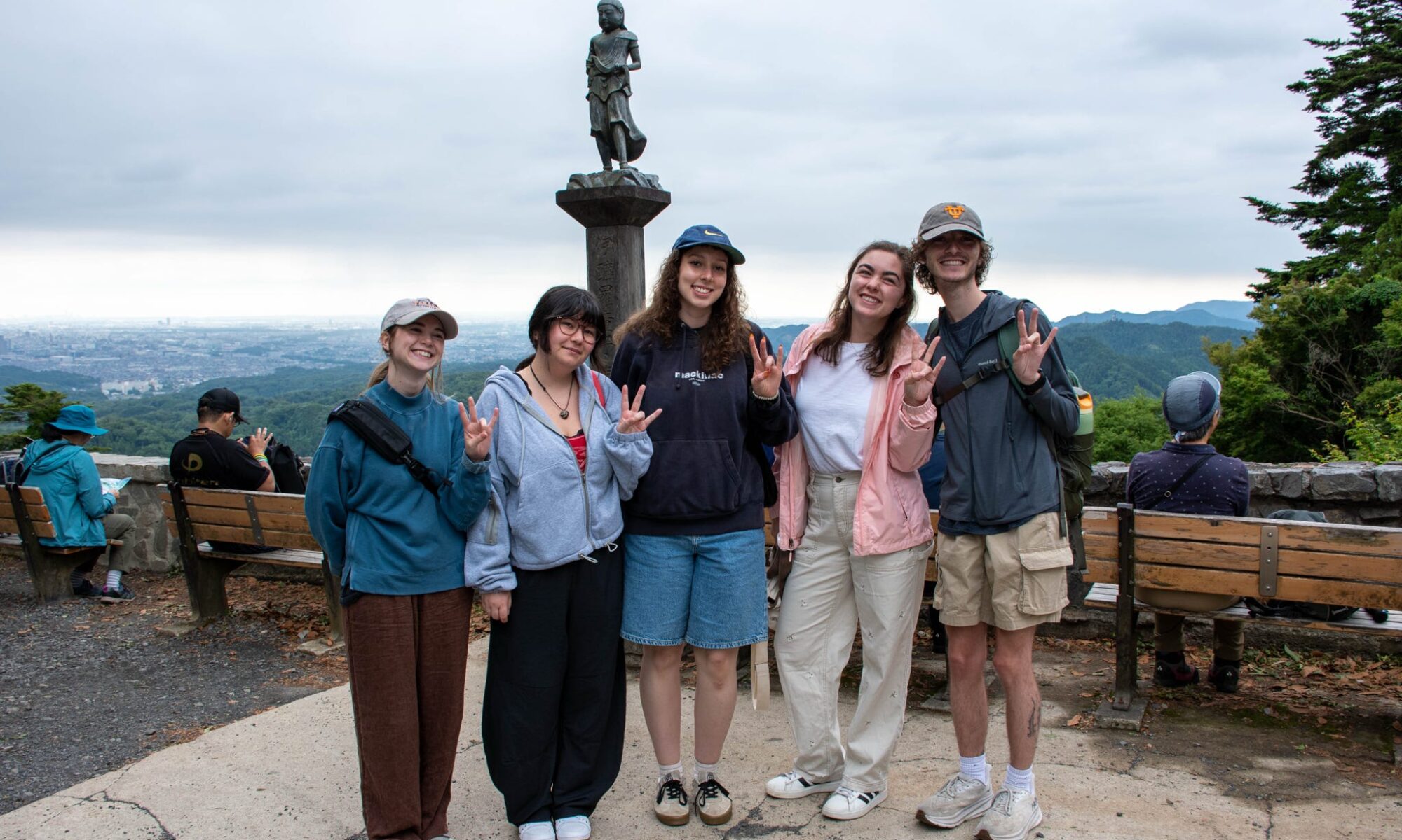 Five students are smiling for a photo with Mt.Takao in the background.