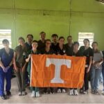 A group of students holding a University of Tennessee flag.
