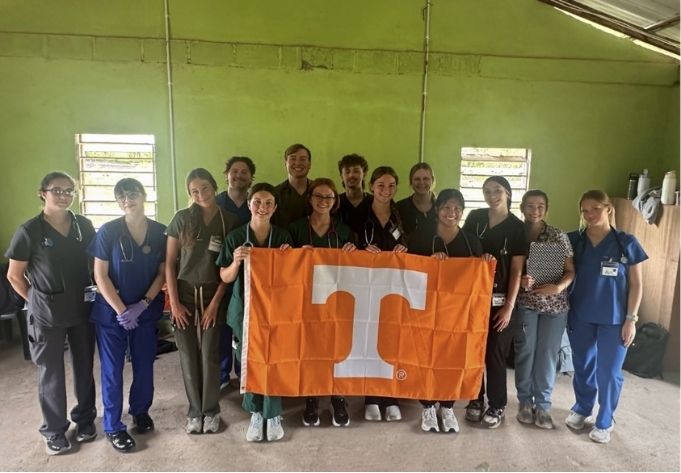 A group of students holding a University of Tennessee flag.