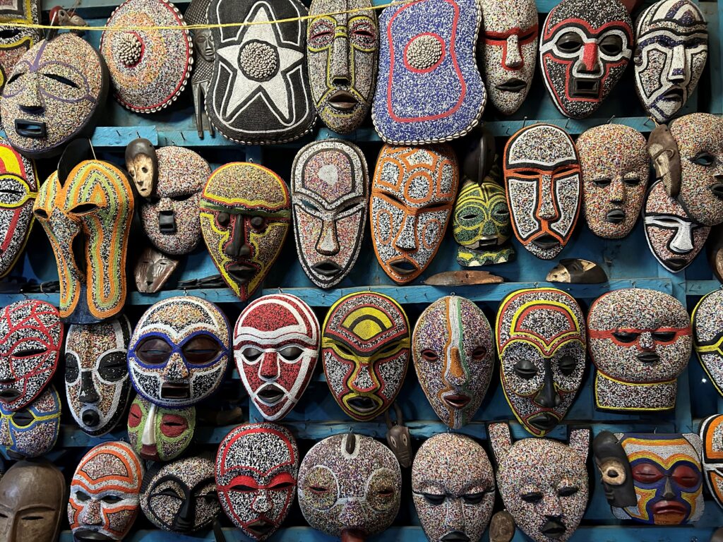 Bright, colorful masks are lined up hanging on a wall.