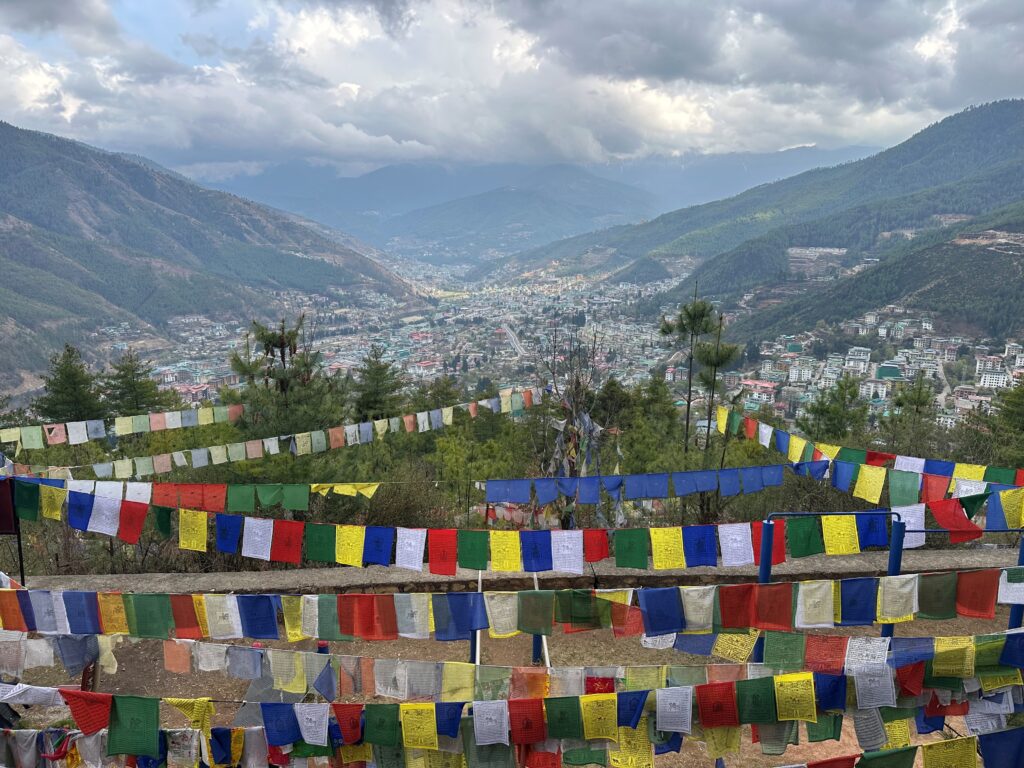 Colorful flags hung up around a landscape with hills.