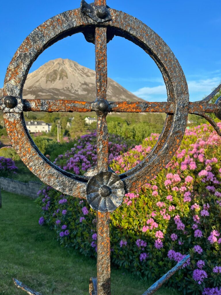 Iron architecture in front of purple flowers and a mountain in the background.