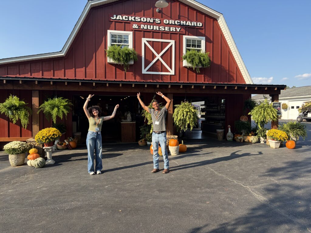 Two students standing in front of a red barn.